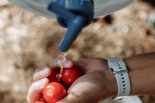 Water running from the spigot of a hanging camp water bag over a pair of hands