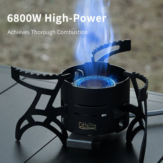Camp stove lit on a folding camp table, showing the vented body and the three folding pot supports