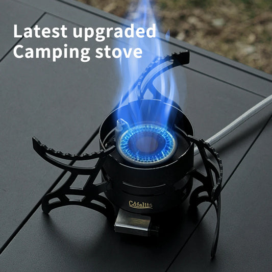 Camp stove burning with a blue flame on a black folding table, three pot supports extended